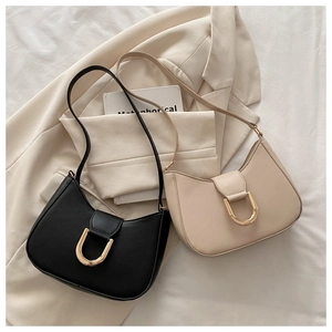 Detail of minimalist leather dumpling bags with large golden U-shaped buckles