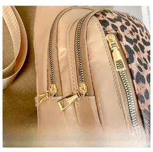 Detail display of high-quality golden metal zippers on a stylish leopard print crossbody bag
