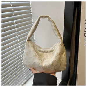 Détail du sac baguette en soie crème avec broderie papillon dorée et fermeture éclair