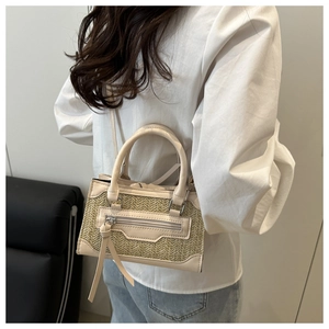 Dettaglio della borsa a tracolla in paglia intrecciata beige con finiture in pelle
