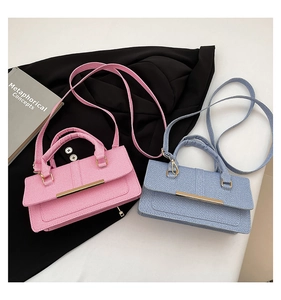 Detail of pink and light blue fabric handbags with gold metal bars and sleek top handles