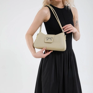 Elegant beige woven underarm bag featuring a silver bow buckle and sleek shoulder strap