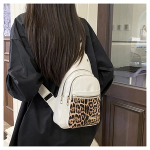 Detail of leopard print patchwork on white leather crossbody bag worn by a model