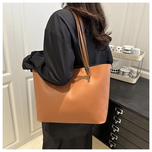 Détail du grand sac cabas en cuir caramel porté par un mannequin en tenue décontractée