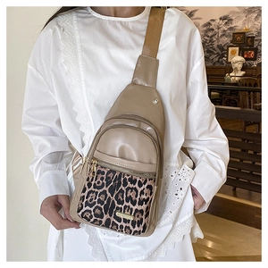 Detail of crossbody chest bag featuring leopard print panels and gold zipper hardware