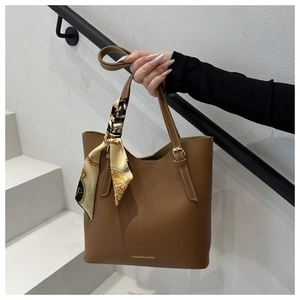 Detail of dark brown leather tote featuring vintage scarf decor and gold logo