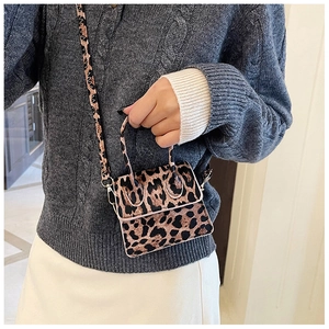 Mini leopard print crossbody bag with fuzzy texture held by model in knit sweater