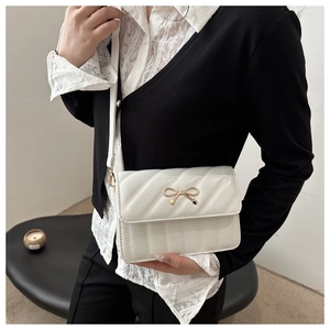 Vue latérale détaillée du sac bandoulière matelassé blanc crème avec boucle noeud doré