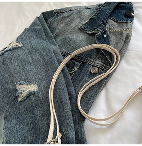 Close-up of distressed denim jacket detail showing collar and metal button accents
