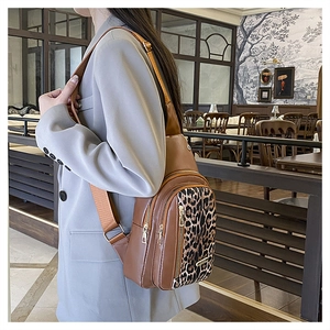 Detail of fashion leopard print crossbody bag worn by model in a stylish cafe setting