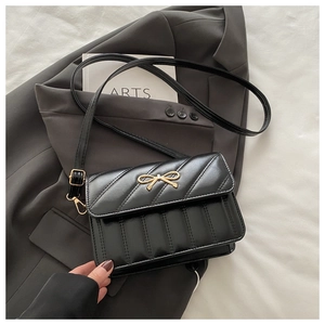 Détail du sac à bandoulière matelassé noir avec boucle nœud doré et sangle en cuir