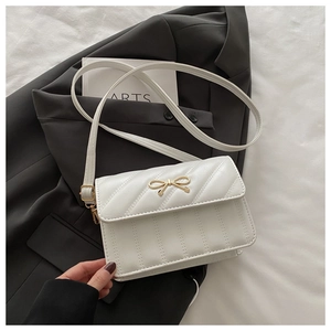 Détail du sac bandoulière matelassé blanc avec nœud en métal doré et texture élégante