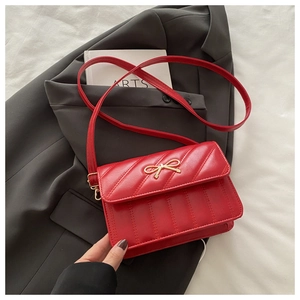 Détail du sac bandoulière en cuir matelassé rouge avec fermoir doré en forme de noeud