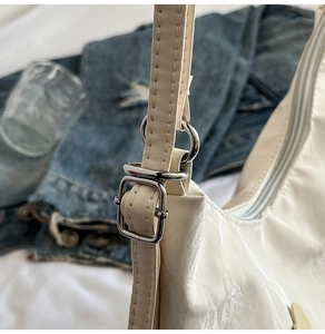 Close-up of silver adjustable metal buckle and strap detail on a cream white tote bag