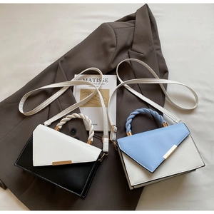 Detail of two-tone crossbody bags featuring woven handles and asymmetric flap closures