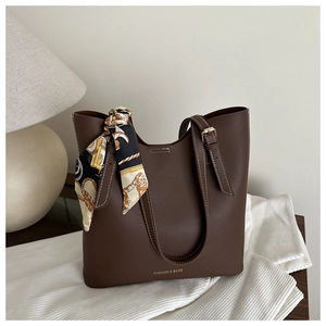 Detail of deep brown tote bag featuring white contrast stitching and a patterned silk scarf