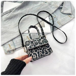Macro shot of leopard print mini square handbag with gold hardware on denim background