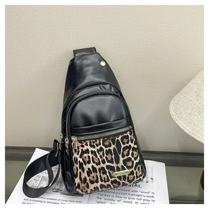 Detail of leopard print panel and gold metal zippers on large black crossbody bag