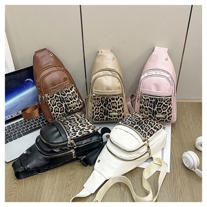 Five leopard print crossbody bags in various colors displayed with lifestyle props