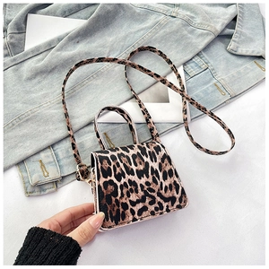 Detailed macro view of leopard print texture on a mini crossbody bag with leather handle