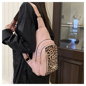 Detail view of pink nylon chest bag with leopard print panel and gold metal zippers
