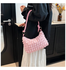 Detailed view of bubble texture material and gold hardware on pink underarm bag