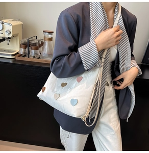 Close-up of white tote bag with colorful heart patches on a shiny wrinkled texture