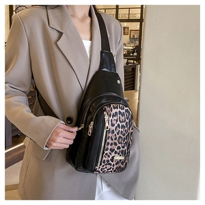 Close-up of leopard print crossbody bag with gold zippers worn over a beige blazer
