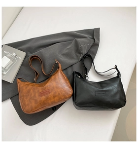 Detail of hobo shoulder bags in brown and black faux leather with metal buckles and branding