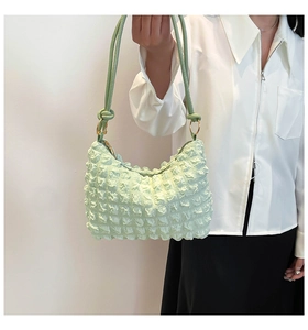 Detail of light green pleated bubble texture handbag with stylish knotted leather shoulder strap