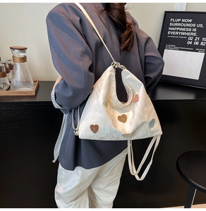 Detailed view of white tote bag with morandi colored heart patches and pleated leather texture