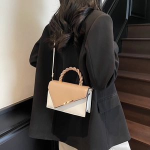 Minimalist square crossbody bag with contrast paneling and woven handle worn by a model