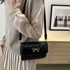 Sac bandoulière élégant en cuir verni noir avec nœud doré et détails de broderie