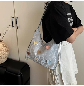 Silver pleated hobo bag featuring colorful heart patches worn by a model in lifestyle setting