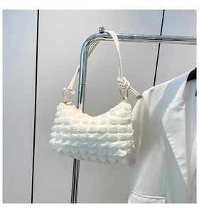 Detailed close-up of white ruched shoulder bag with textured bubble fabric and knotted strap