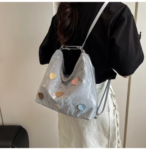 Silver metallic backpack with colorful heart patches shown on a model's back