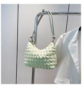 Close-up of mint green pleated hobo bag with popcorn texture and golden ring buckle