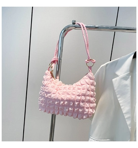 Detail of pink pleated hobo bag featuring bubble texture fabric and golden ring hardware