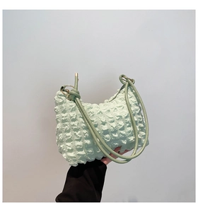 Close-up of light green bubble textured fabric and knot detail on a fashion handbag