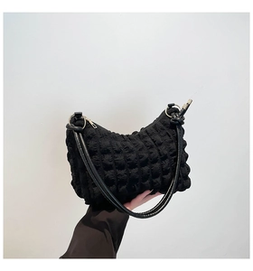 Close-up of black bag featuring bubble texture quilting and metal ring strap detail