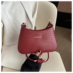 Detail of wine red woven leather handbag featuring a knotted strap and gold hardware