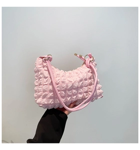 Macro shot of pink pleated bubble texture and gold metal ring on a soft shoulder bag