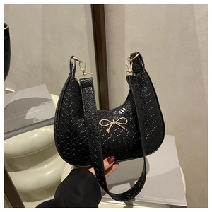 Close-up of black hobo bag with woven texture and a gold bow fastener buckle