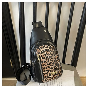 Detail of leopard print chest bag with golden zippers on a textured chair cushion