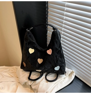 Detail of black wrinkled texture bag with colorful heart patches and adjustable straps