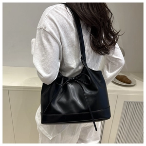 Vue détaillée du sac cabas noir avec nœuds porté par un mannequin dans une pièce minimaliste