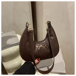 Detail of dark brown woven crescent bag with golden bow and metal zipper hardware