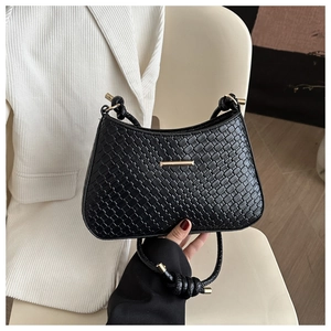 Detailed view of black woven texture on mini square bag with golden hardware accents