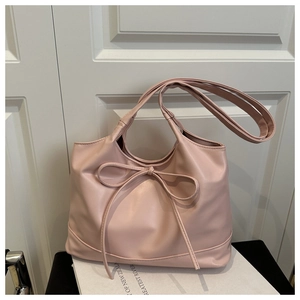 Détail d'un grand sac cabas rose en cuir ciré avec un nœud décoratif et des surpiqûres
