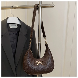 Detail of dark brown woven texture hobo bag with a golden bow metal accessory